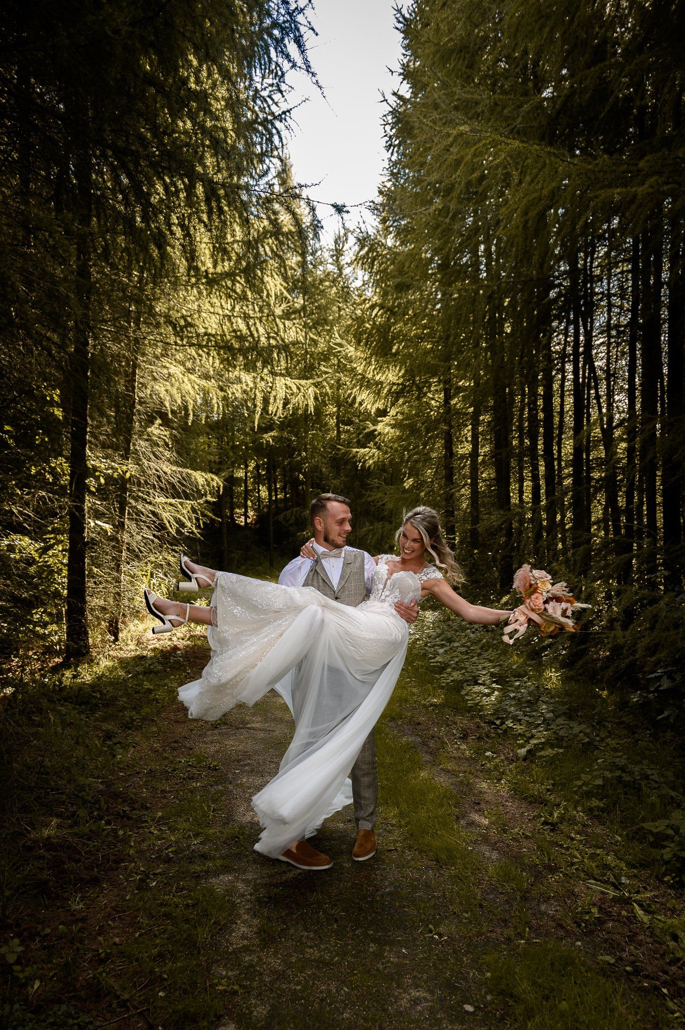 Een bruid en bruidegom dansen in het bos op hun bruiloft.