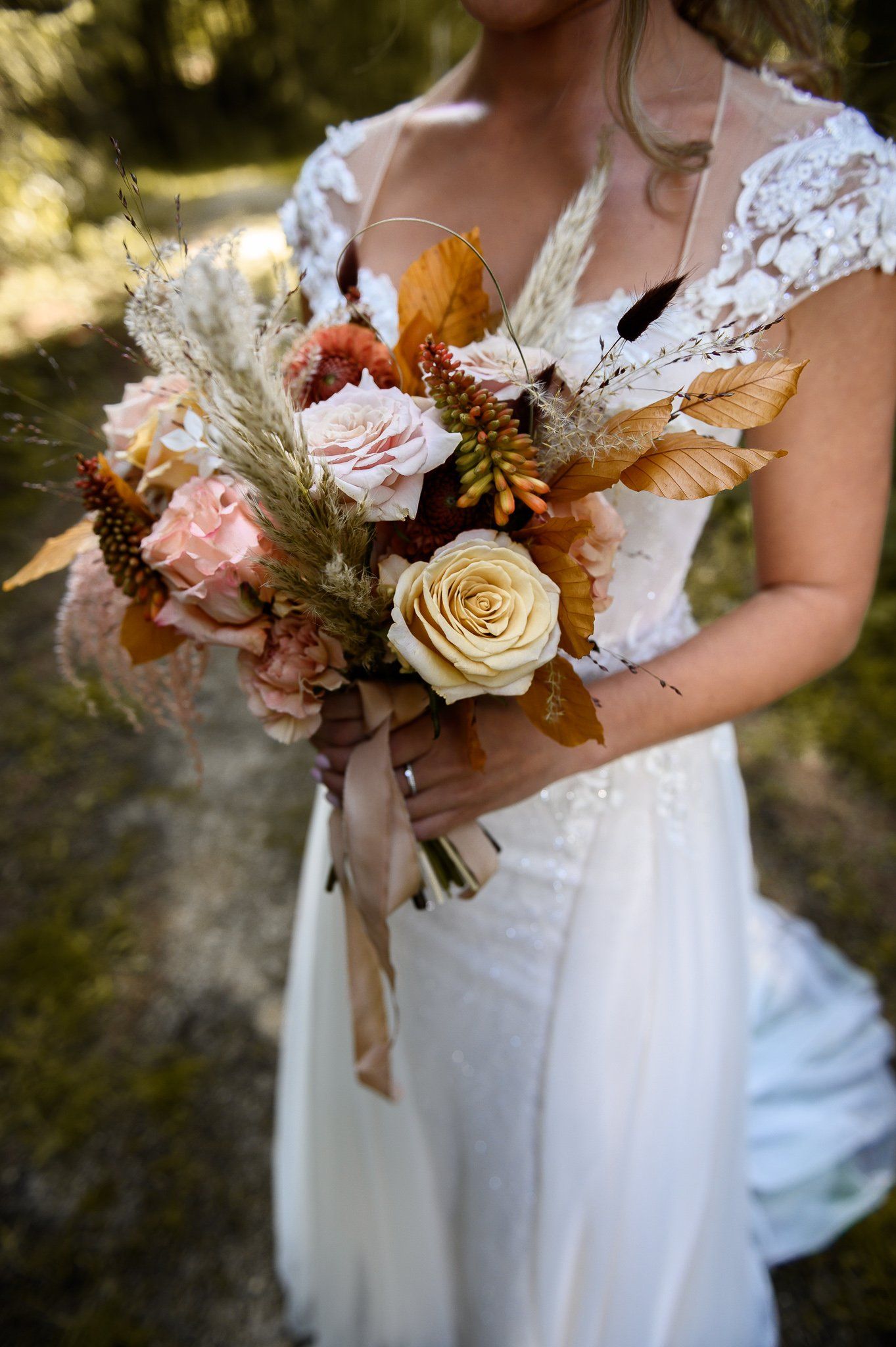Een bruid in een witte jurk houdt een boeket bloemen vast.
