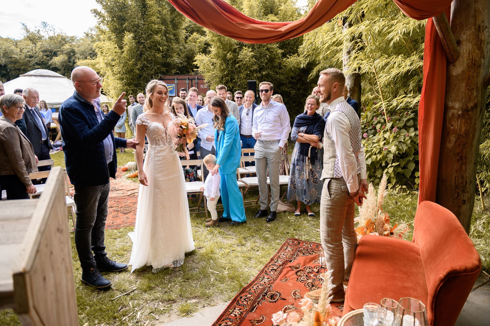 Een bruid en bruidegom staan voor een menigte mensen tijdens hun huwelijksceremonie.