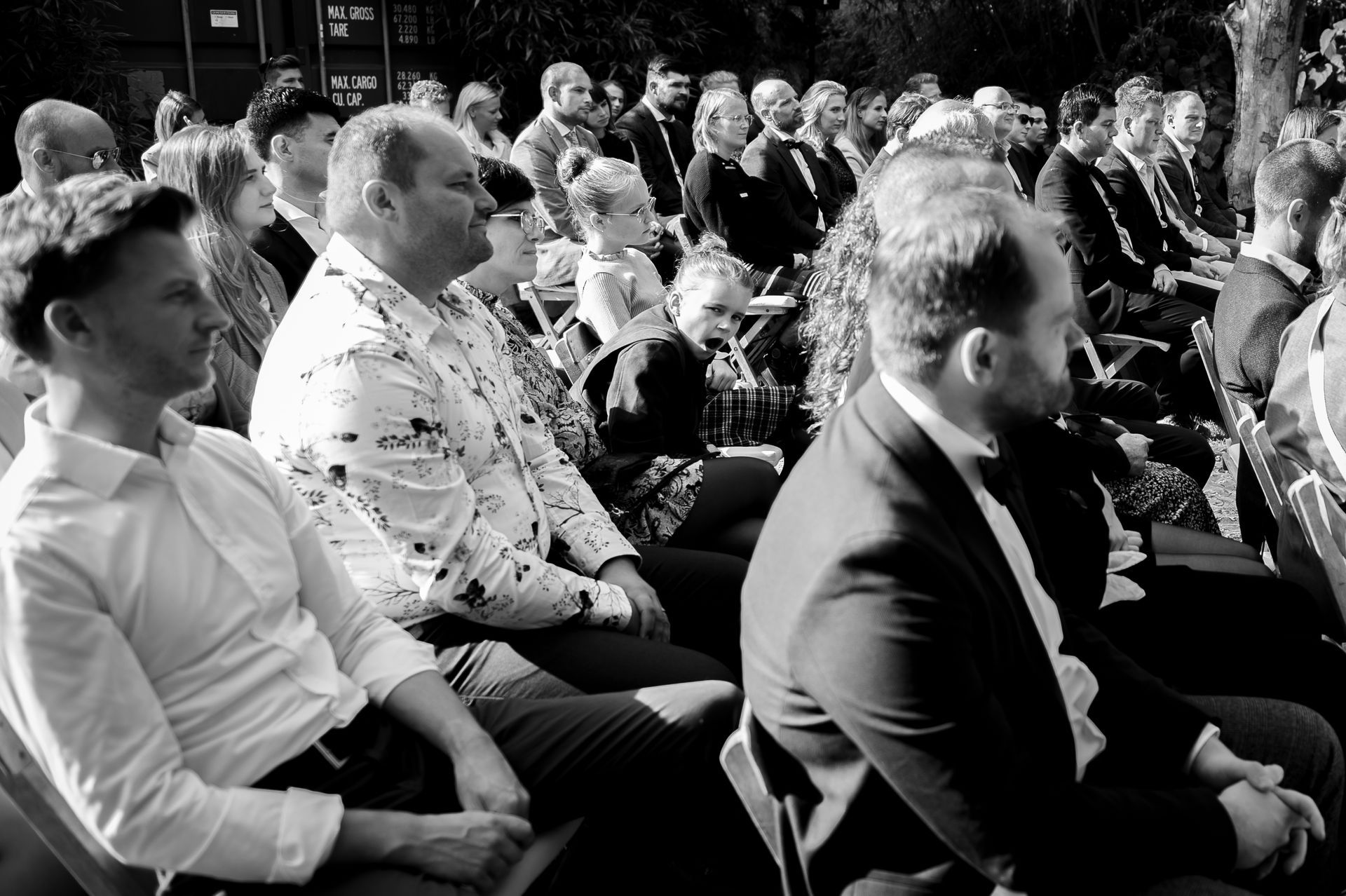 Een zwart-witfoto van een groep mensen die op stoelen zitten.