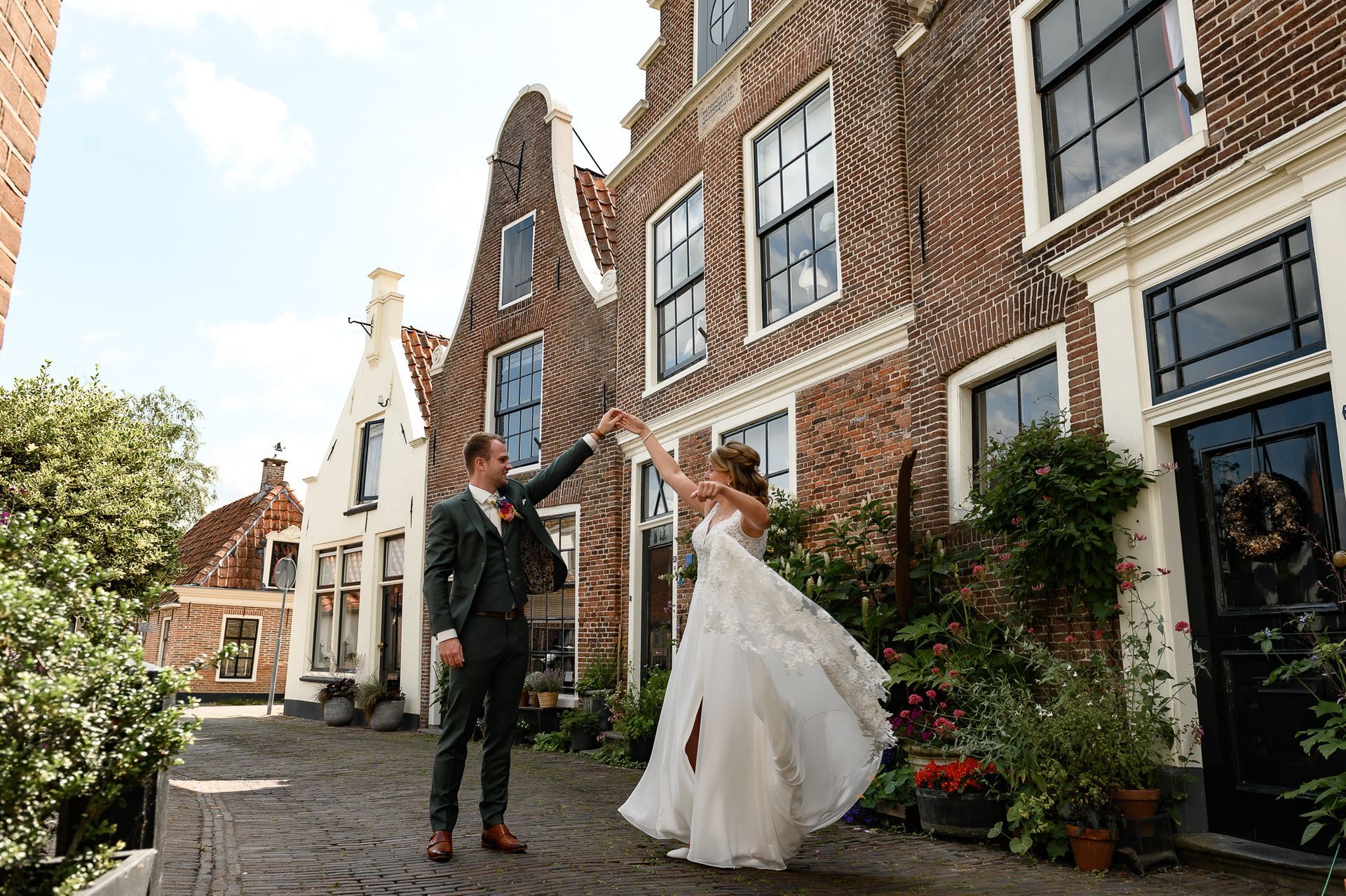 Een bruid en bruidegom dansen in een straat.