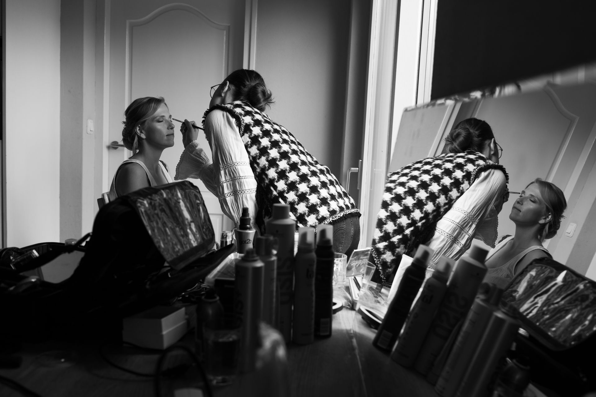 Een bruid laat zich opmaken voor de spiegel.