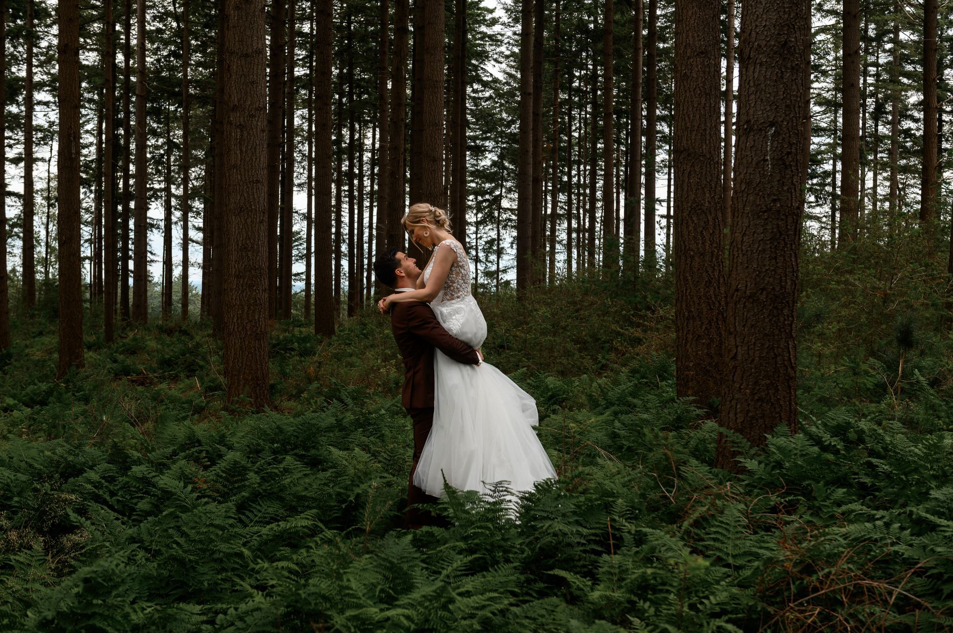Een bruid en bruidegom staan midden in een bos.