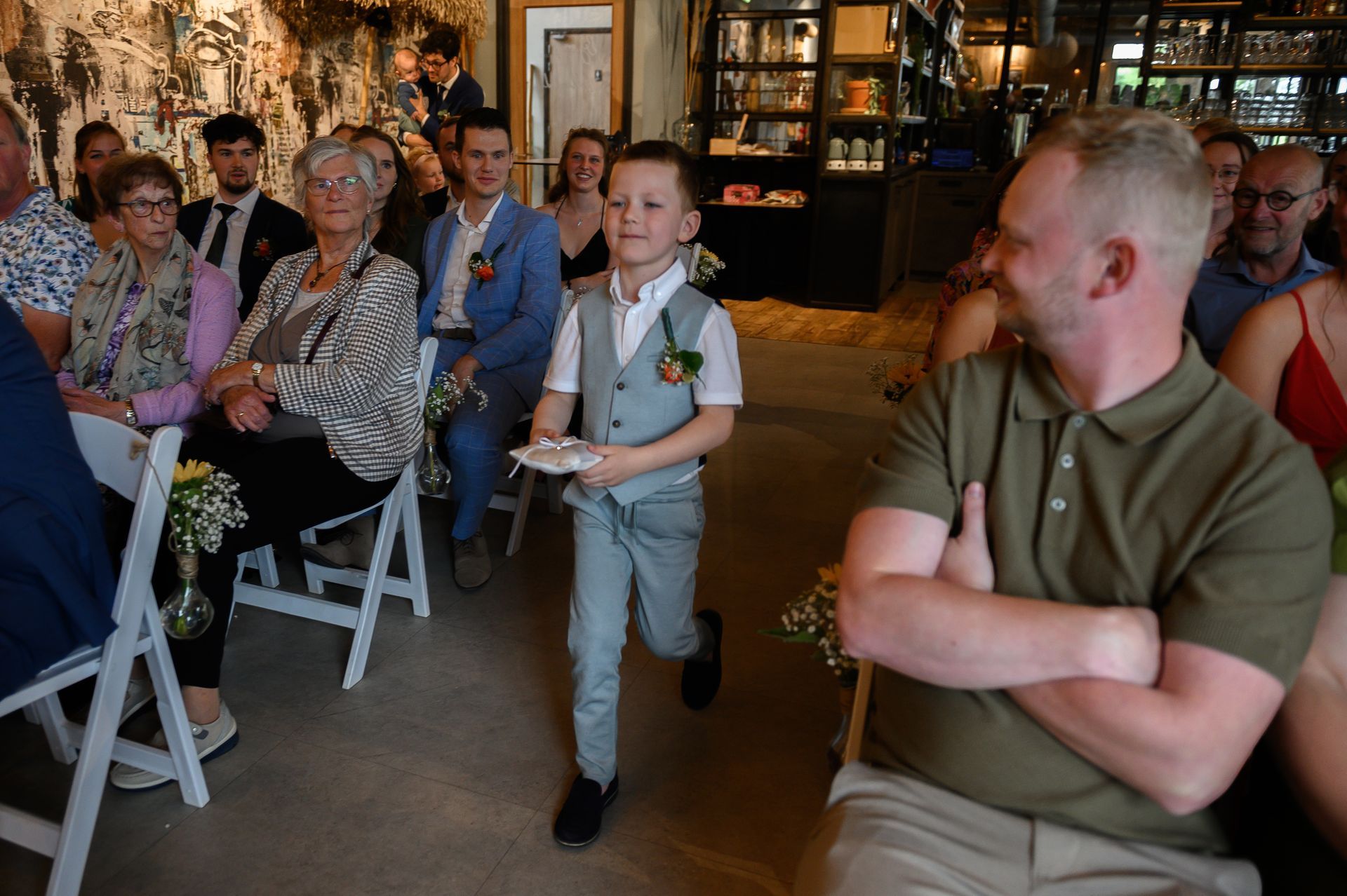 Een jongen in een pak loopt naar het altaar op een bruiloft met de ringen.