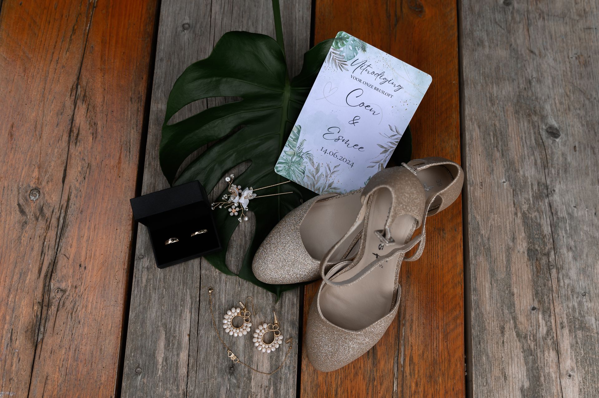 Een paar schoenen, oorbellen, een ring en een kaartje liggen op een houten tafel.