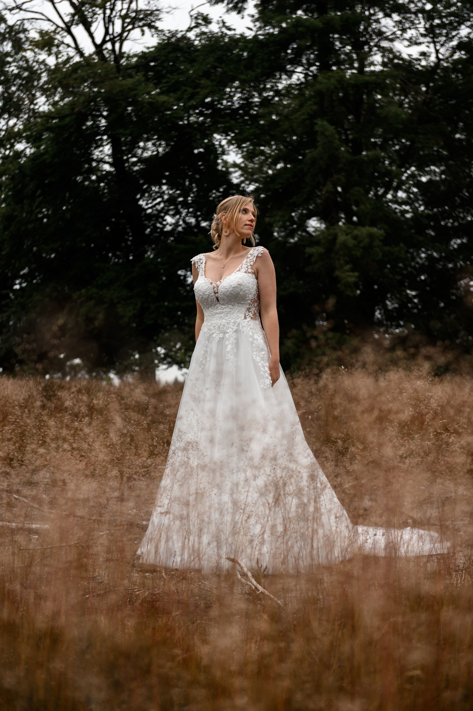 Een bruid in een trouwjurk staat in een veld.