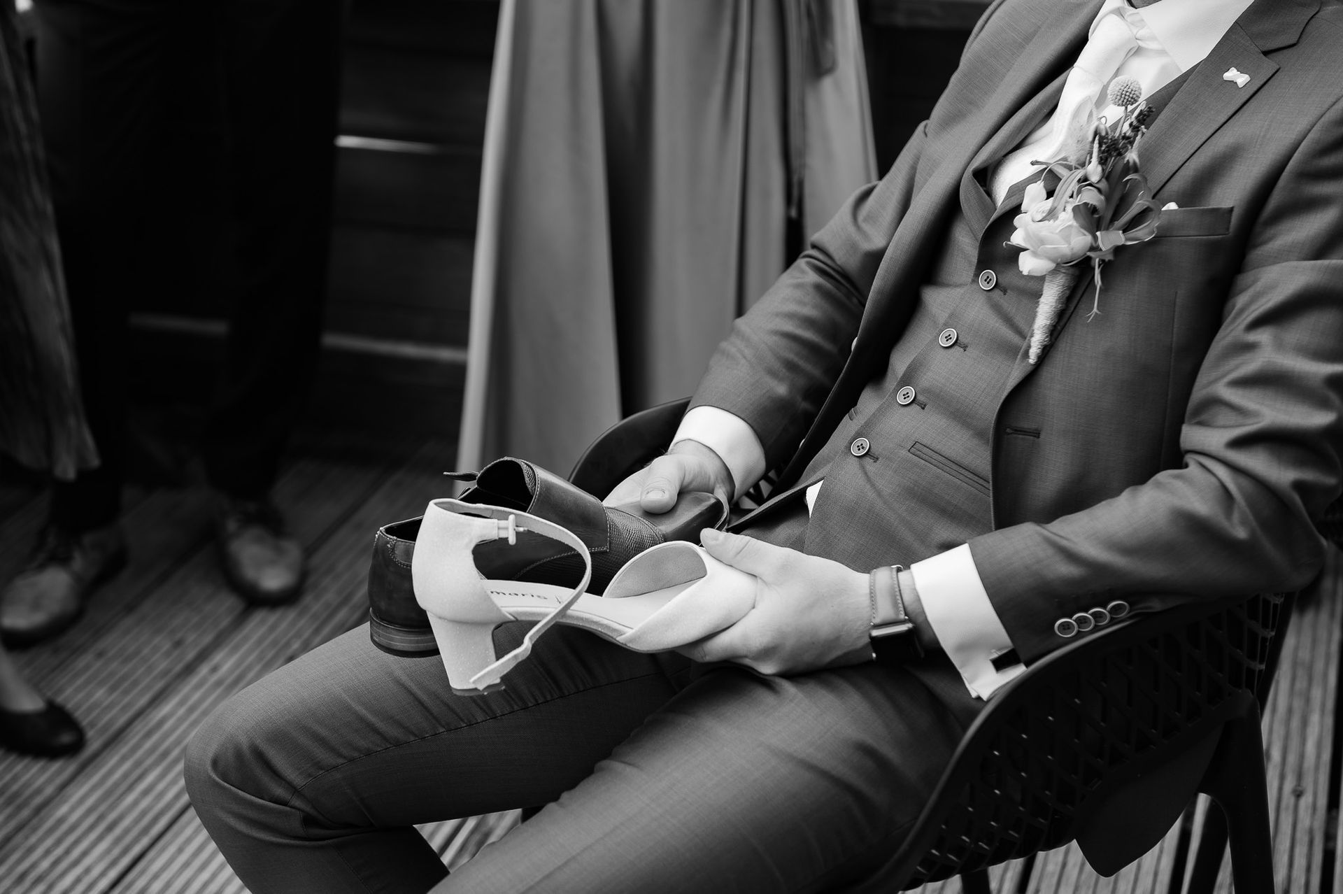 Een bruidegom zit op een stoel met een paar schoenen in zijn handen.