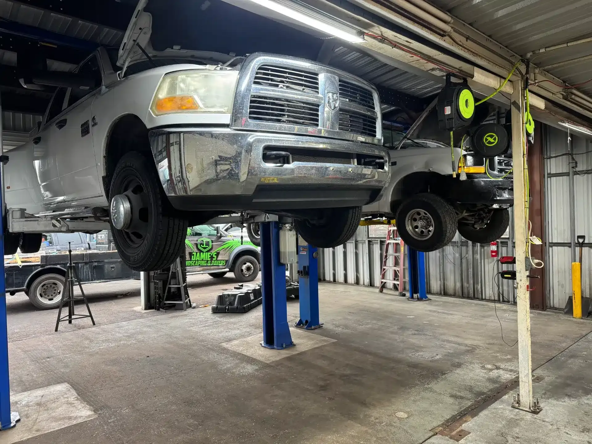 Two white trucks raised up in garage | DMR Diesel Repair, Inc