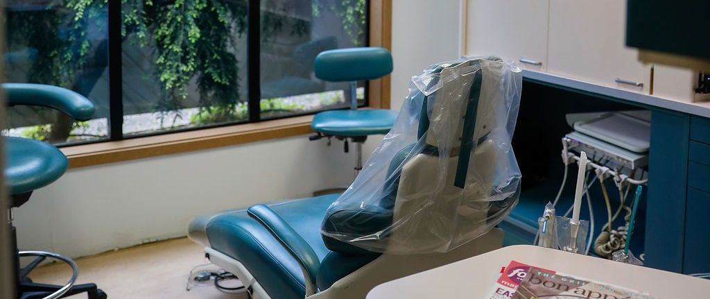 A woman is sitting in a dental chair in a dental office.
