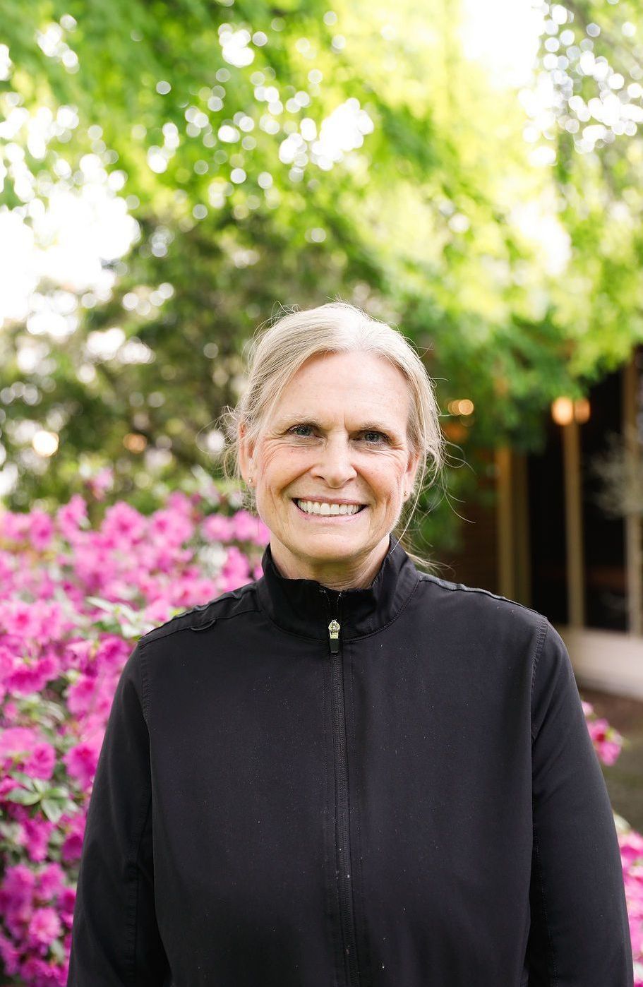 A woman in a green and white shirt is smiling for the camera.