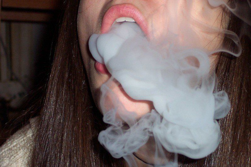 A woman is blowing smoke out of her mouth.