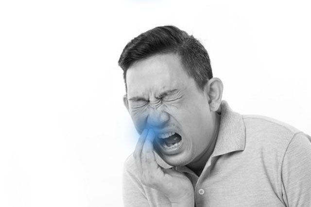 A man is holding his mouth in pain because of a toothache.