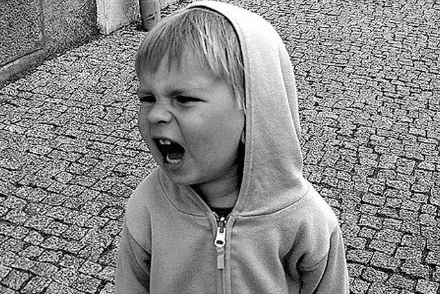 A black and white photo of a little boy wearing a hoodie.