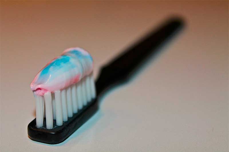 A close up of a toothbrush with toothpaste on it.