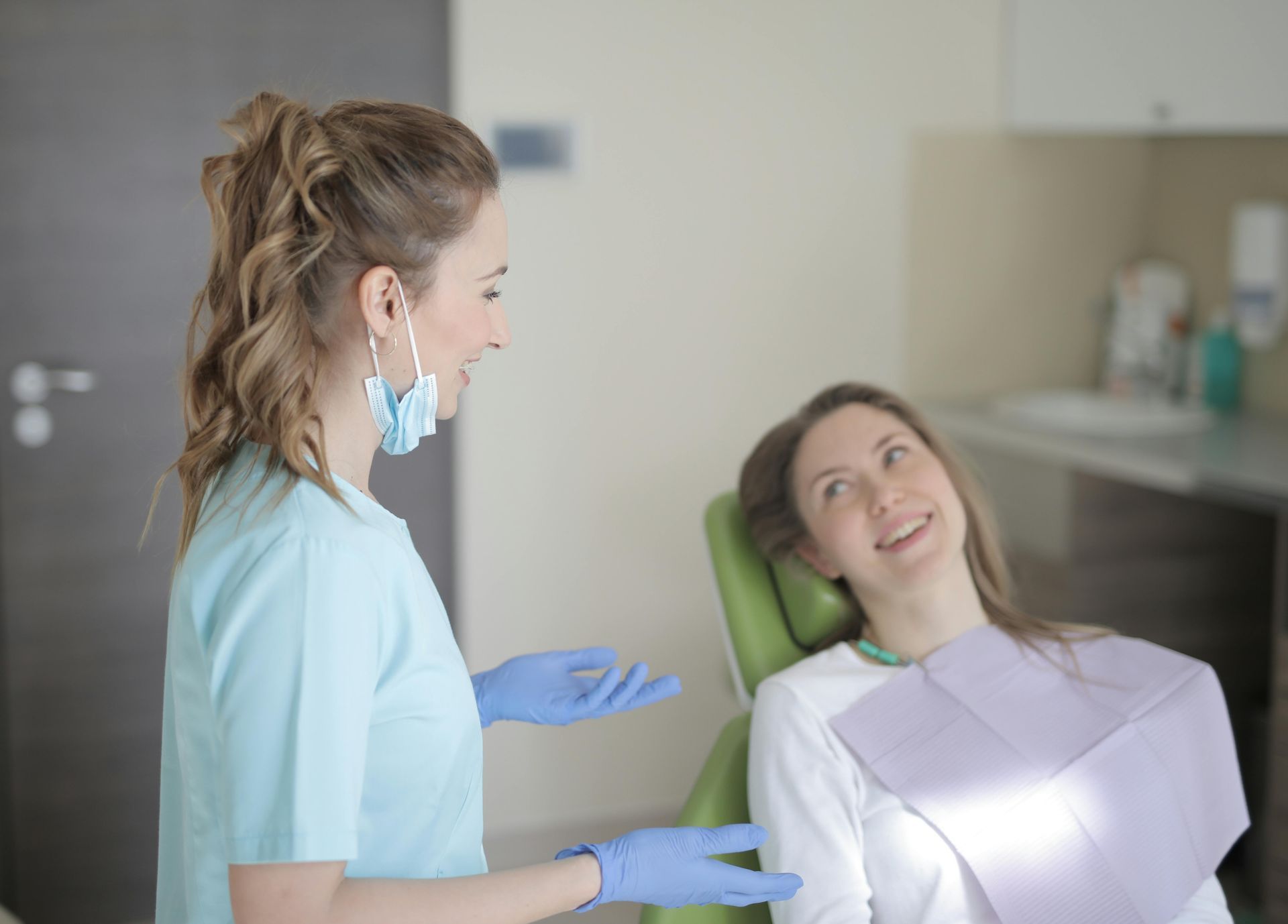 A dentist is talking to a patient in a dental chair.
