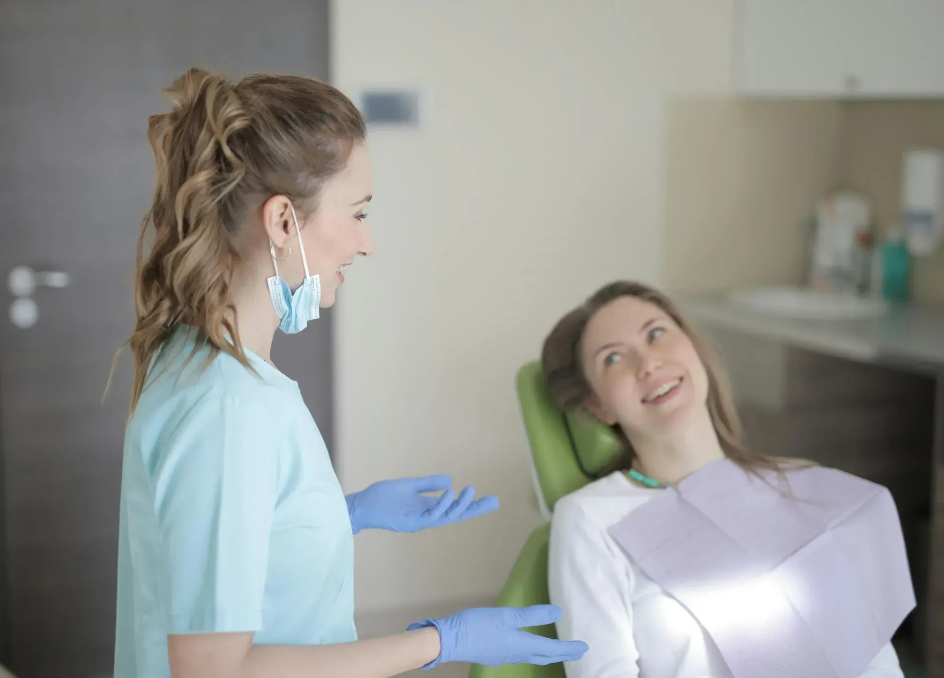 A dentist is talking to a patient in a dental chair.