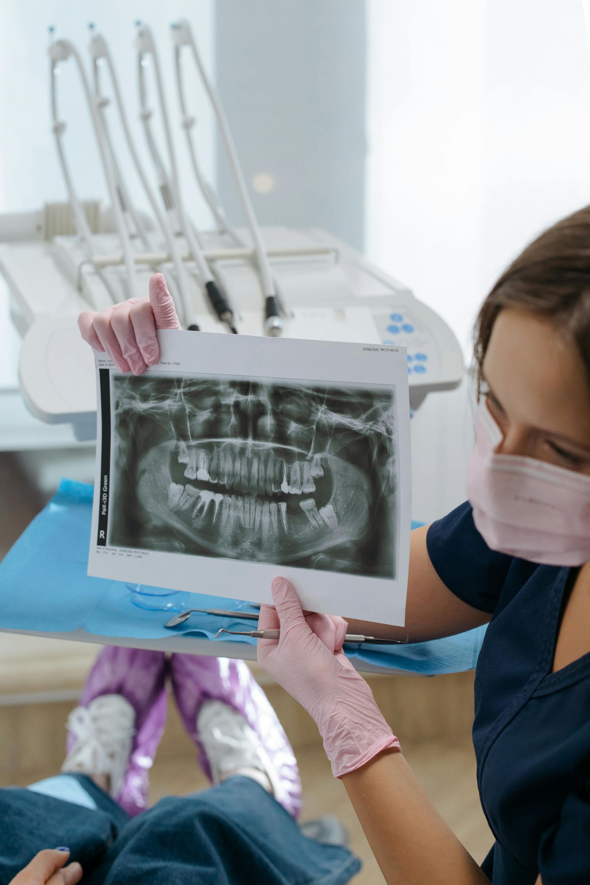 Dentist holding up dental x-ray in front of patient in examination chair.