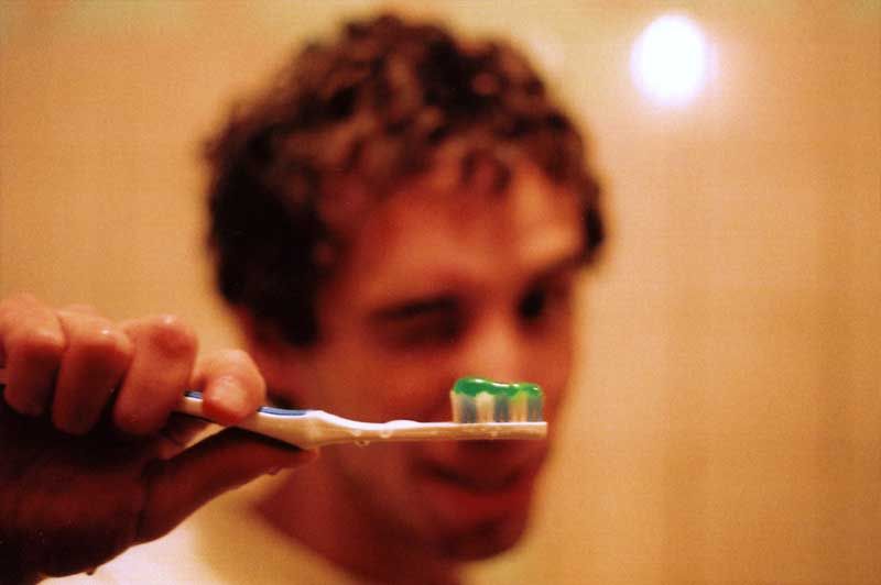 A man is brushing his teeth with green toothpaste