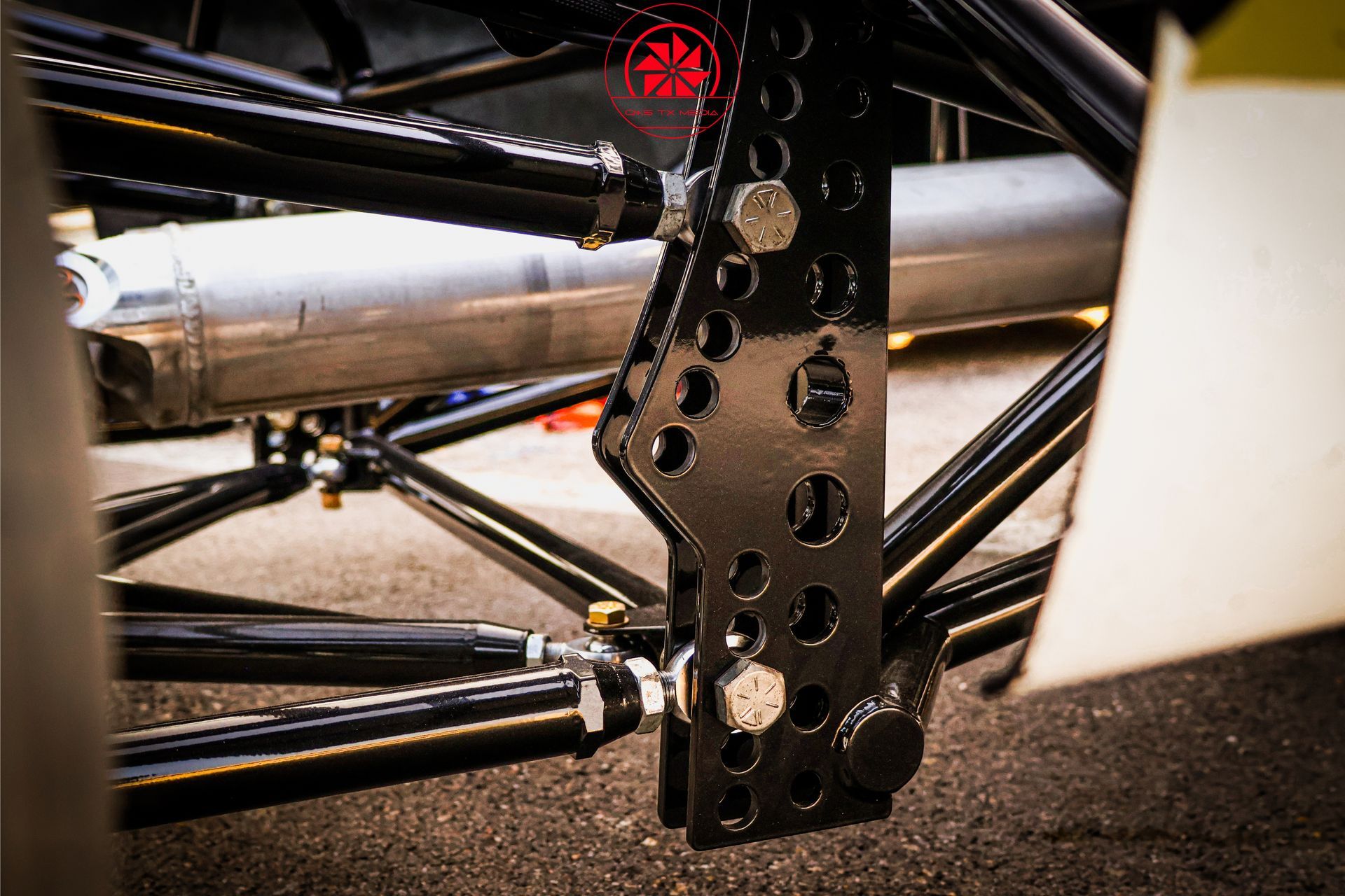 Close-up of a black metal suspension or chassis component on a vehicle with white body panels