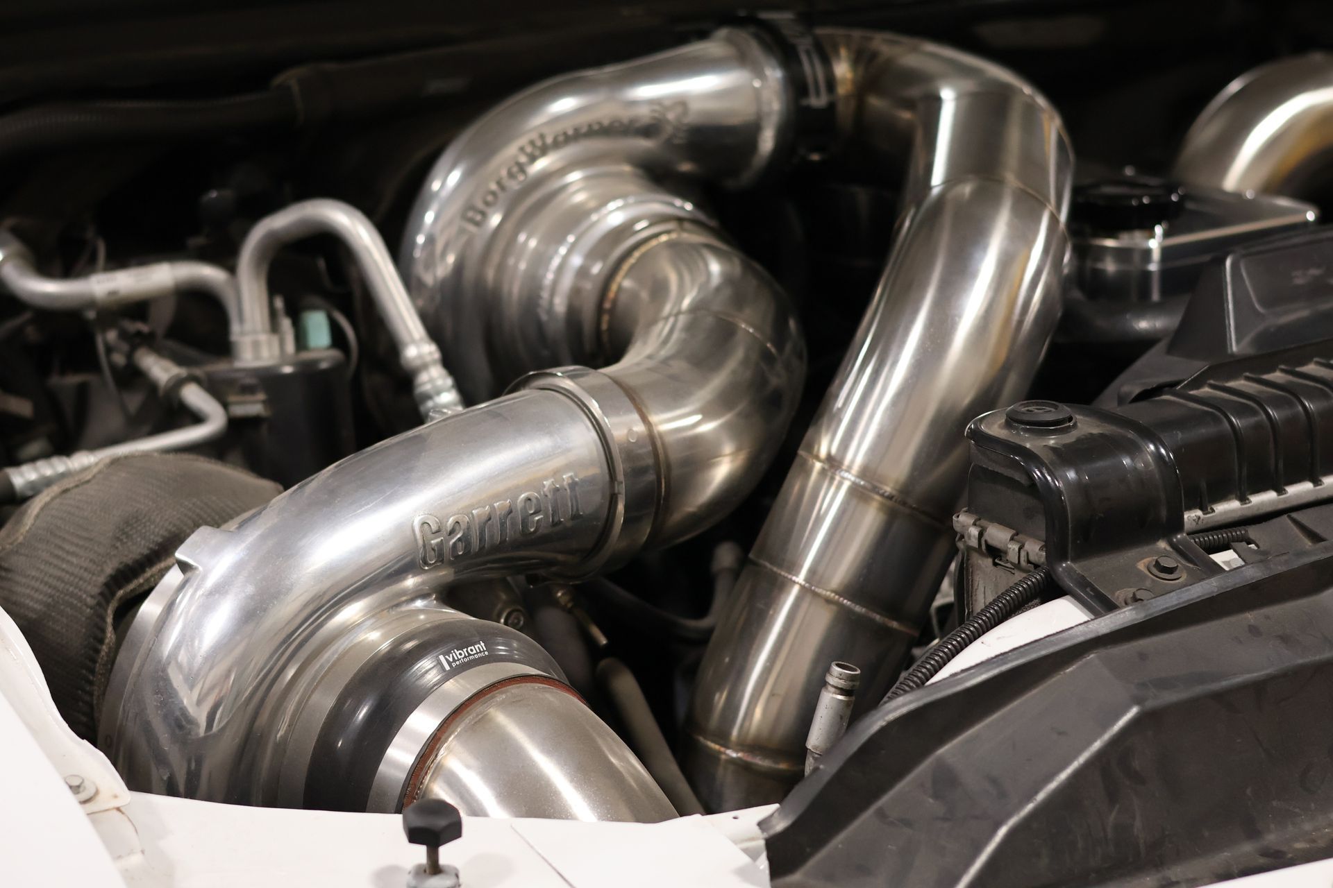 Shiny metal car engine piping and turbo tubing in a close-up under the hood
