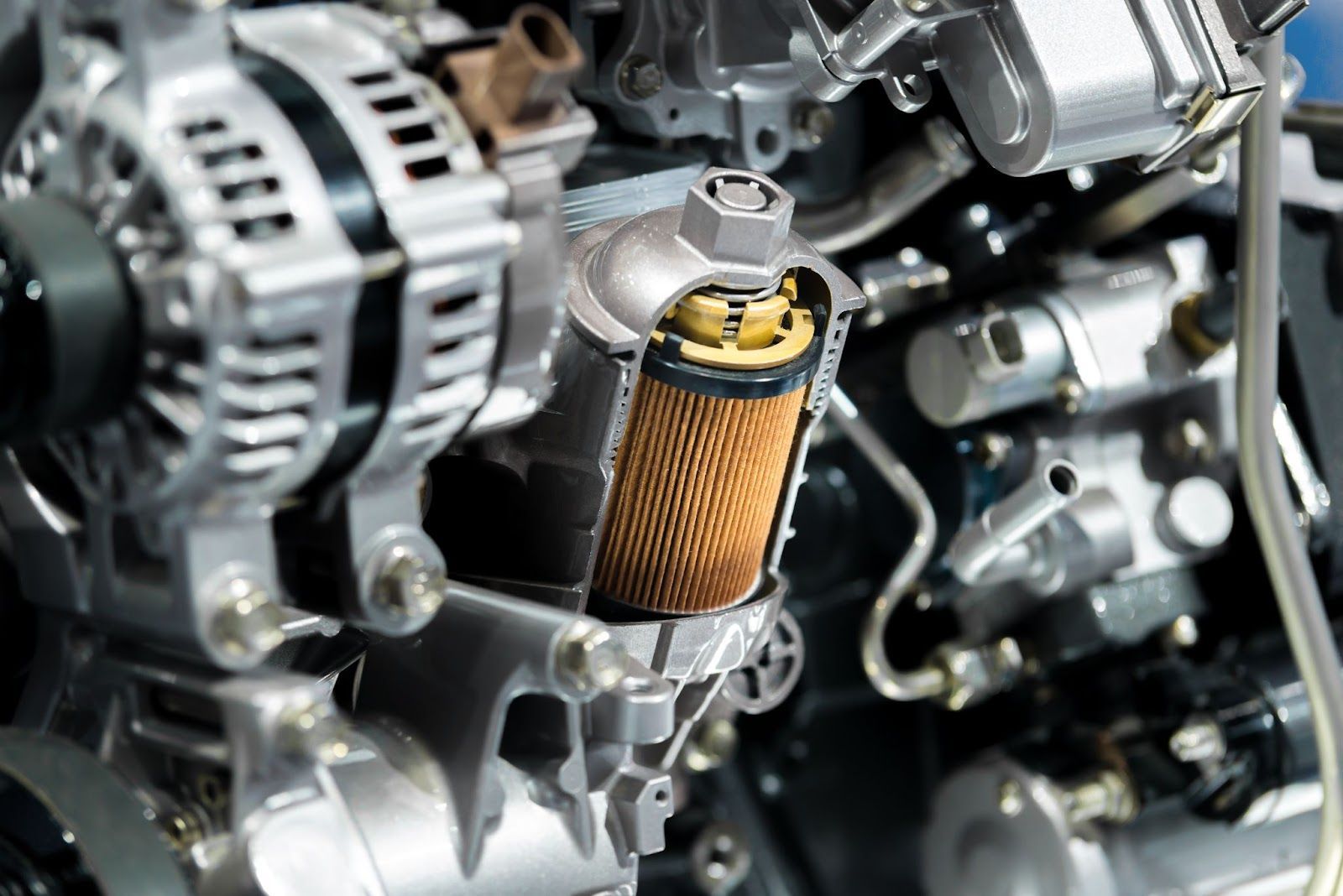 Close-up of a car engine with an orange oil filter and silver metal components