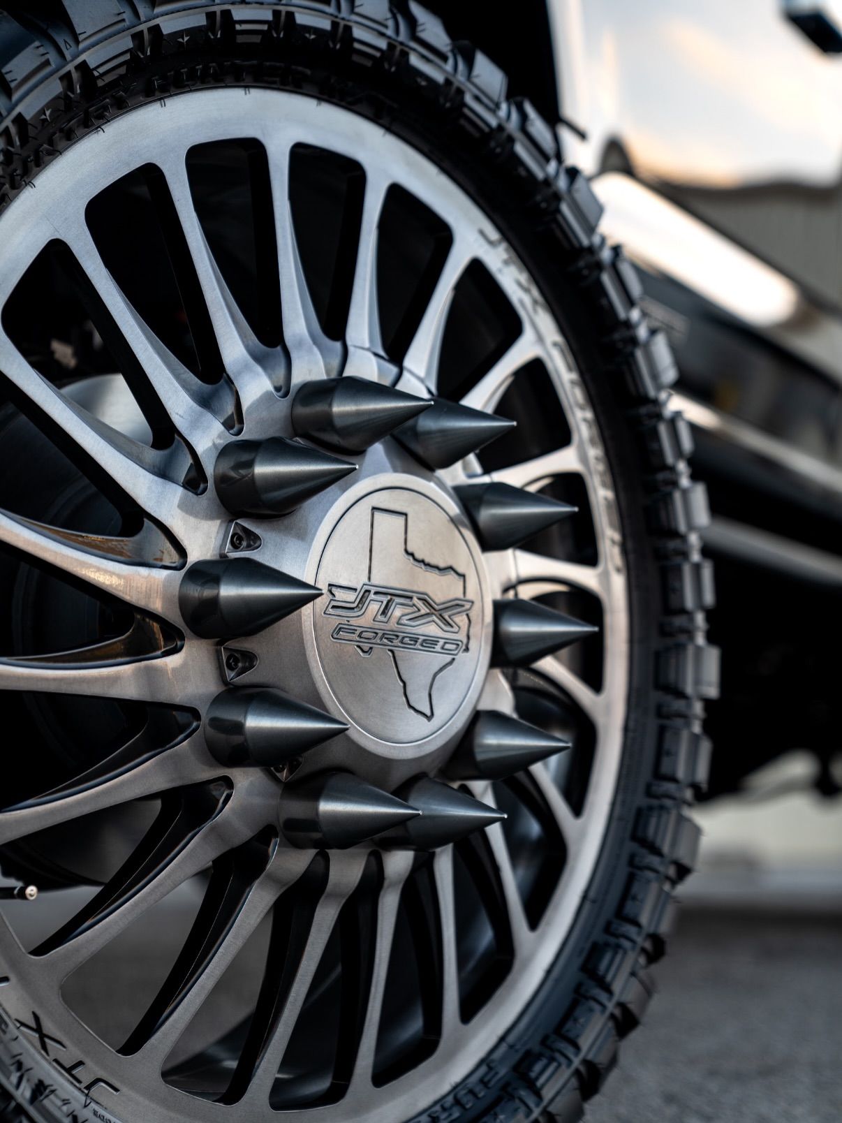 Close-up of a rugged black alloy wheel with off-road tire and skull-style center cap