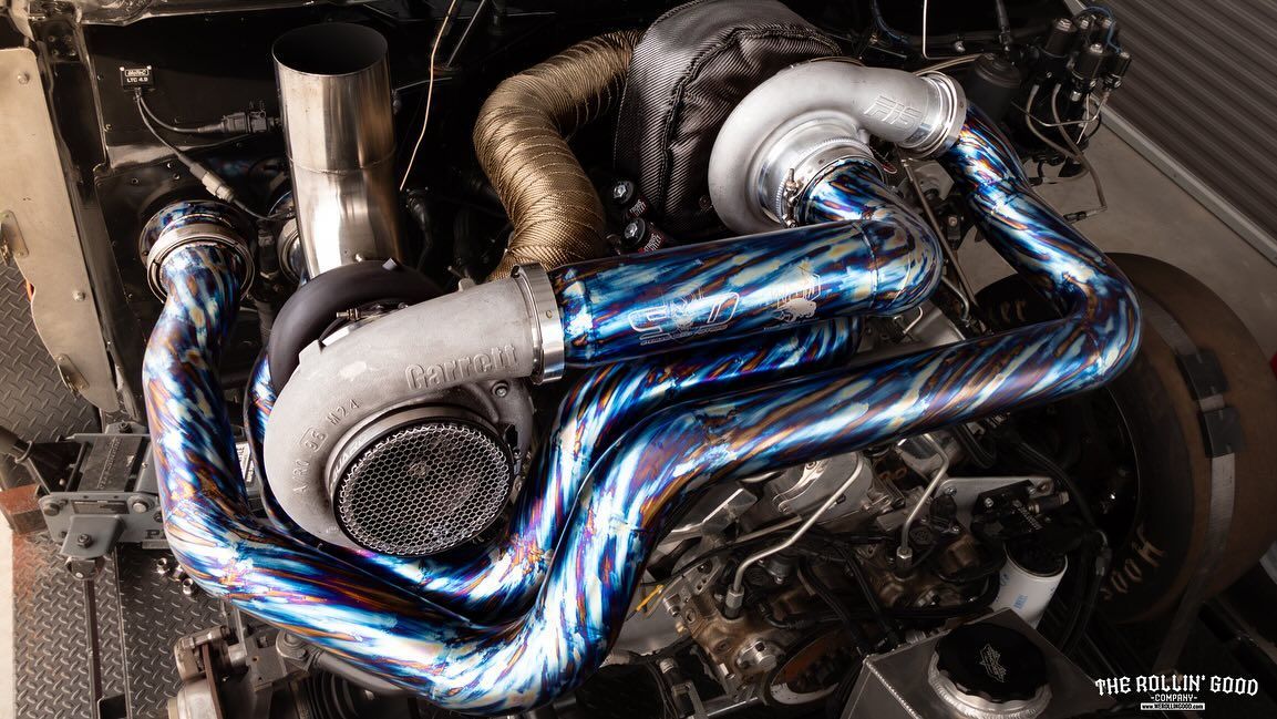 Close-up of a car engine bay with shiny blue heat-wrapped exhaust pipes and metal components