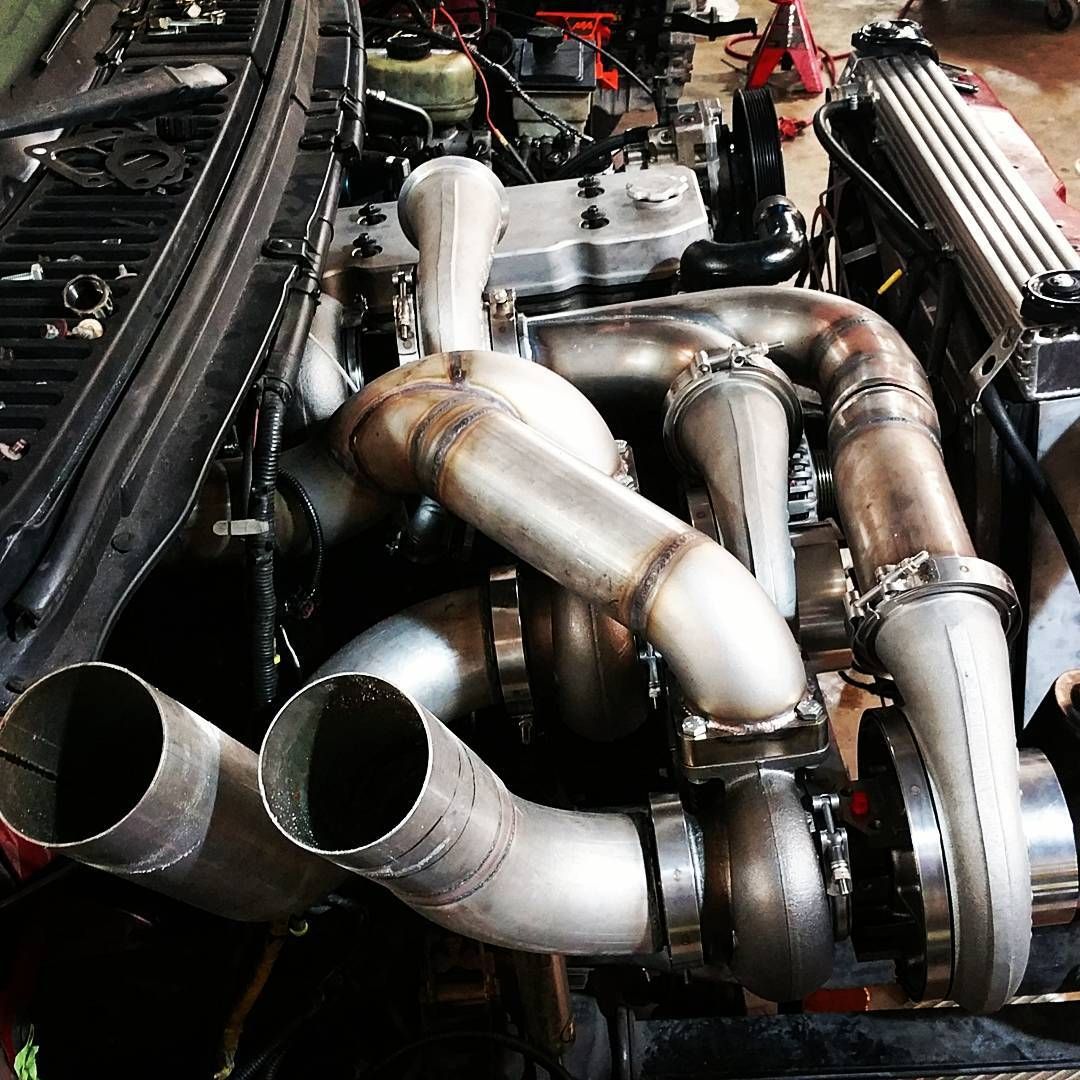 Shiny stainless steel turbo manifold and twin exhaust pipes in an engine bay