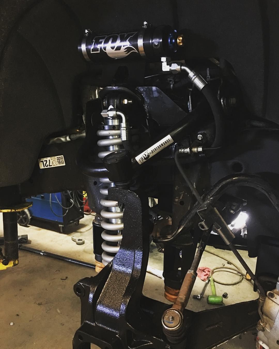 Black motorcycle suspension close-up on a repair stand in a dark garage