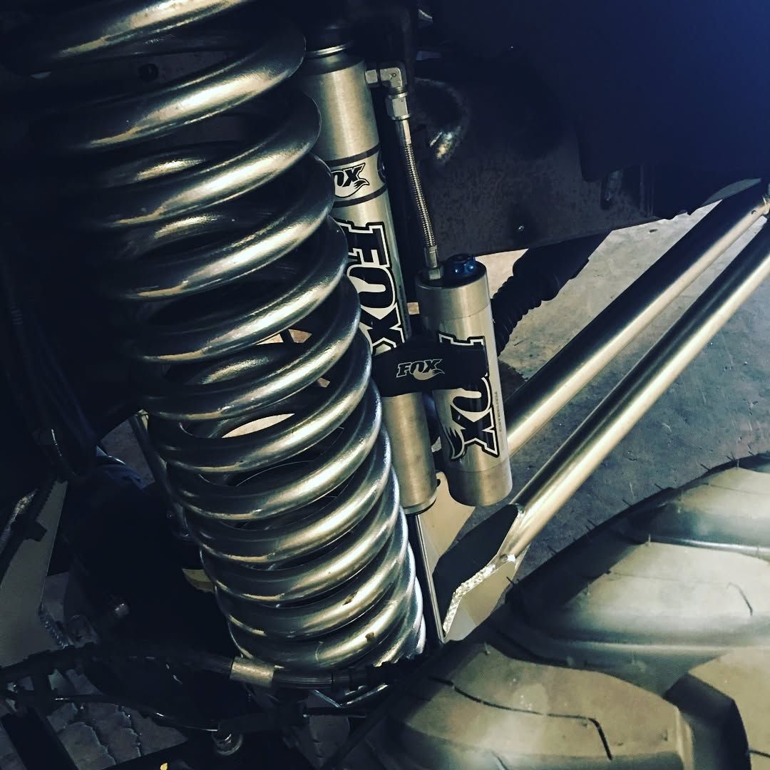 Close-up of a car suspension coil spring and shock absorber inside the wheel well.