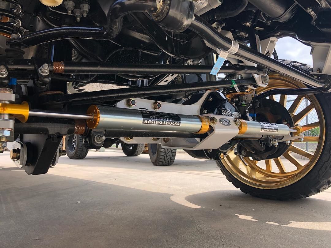 Chrome exhaust pipe beneath a vehicle with gold wheels