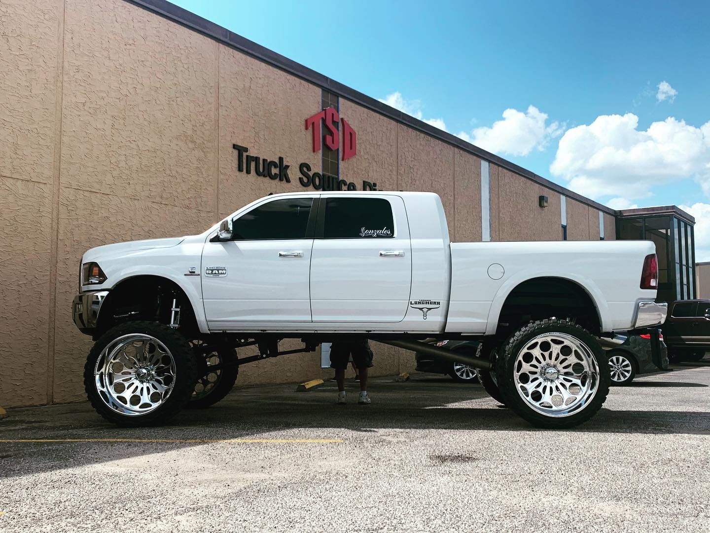 White lifted pickup truck parked outside a truck accessory shop