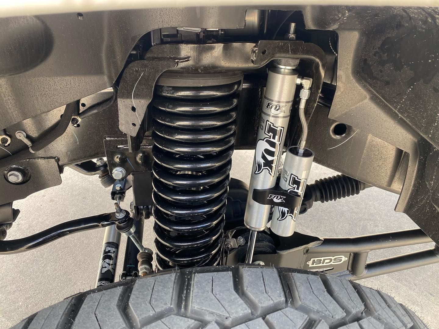 Close-up of a vehicle suspension with coil spring, shock absorber, and front tire