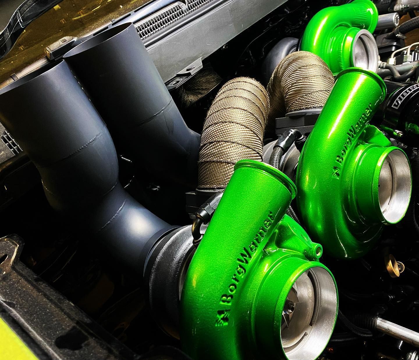 Close-up of green and black turbochargers and engine components in a car engine bay