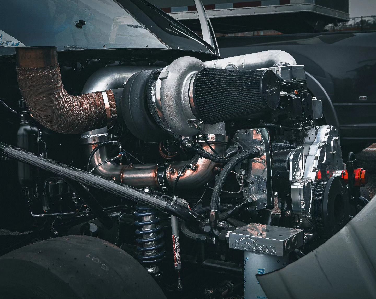 Close-up of a car engine with turbocharger, exposed metal piping, and dark mechanical components.