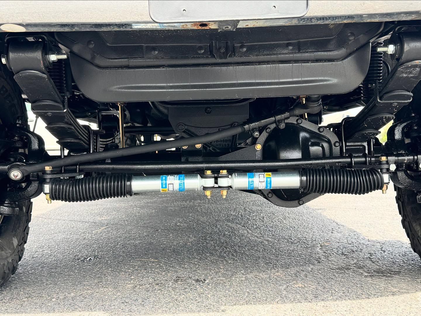 Undercarriage view of a lifted vehicle with off-road suspension and steering components visible