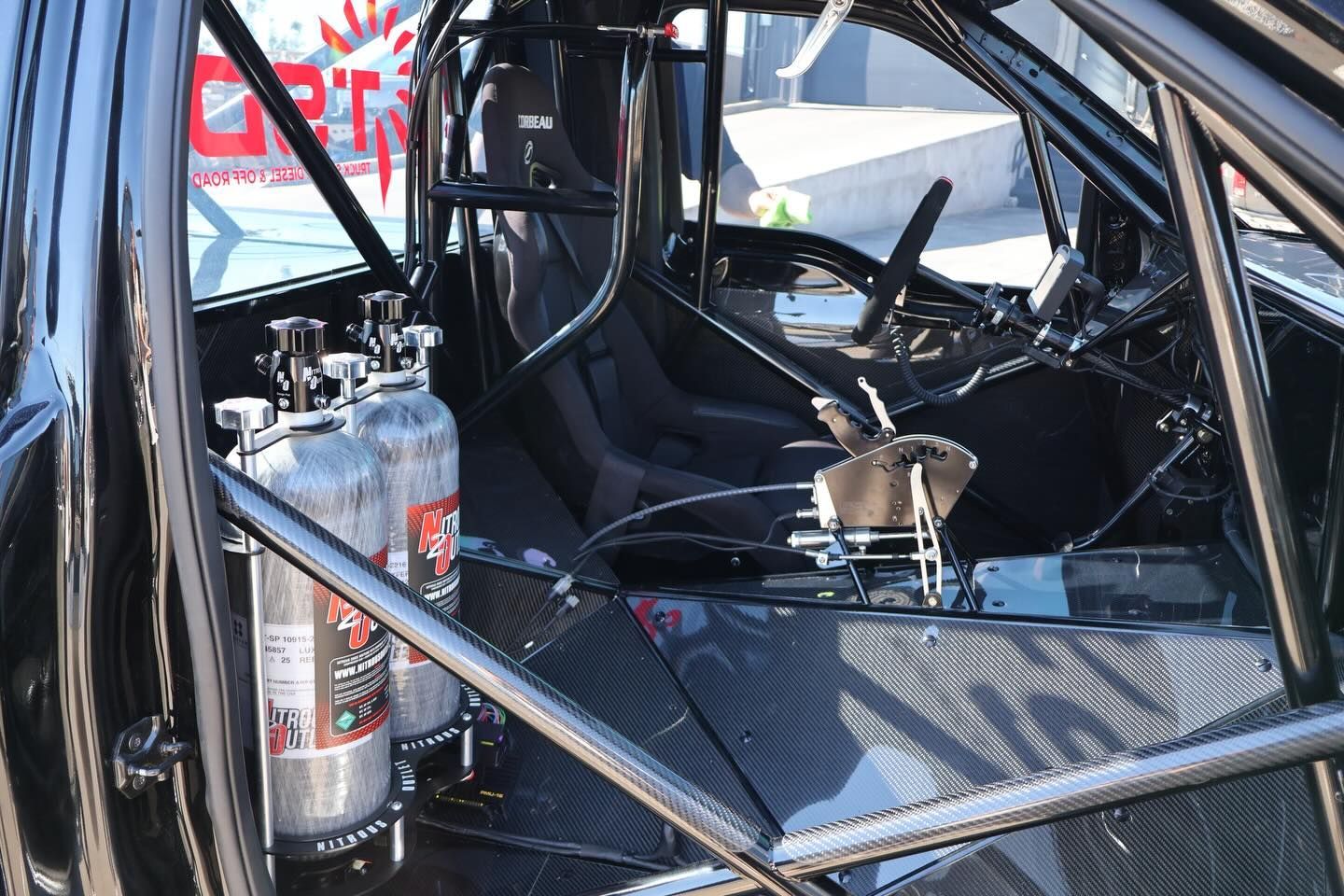 Roll cage interior of a race car with a fire extinguisher and a loose seat inside