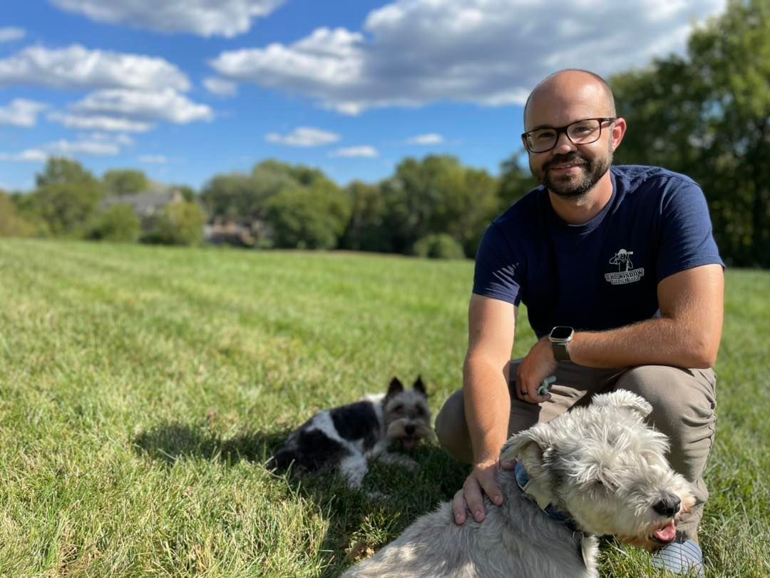 A man is standing in front of a window with a rainbow reflected in it.
