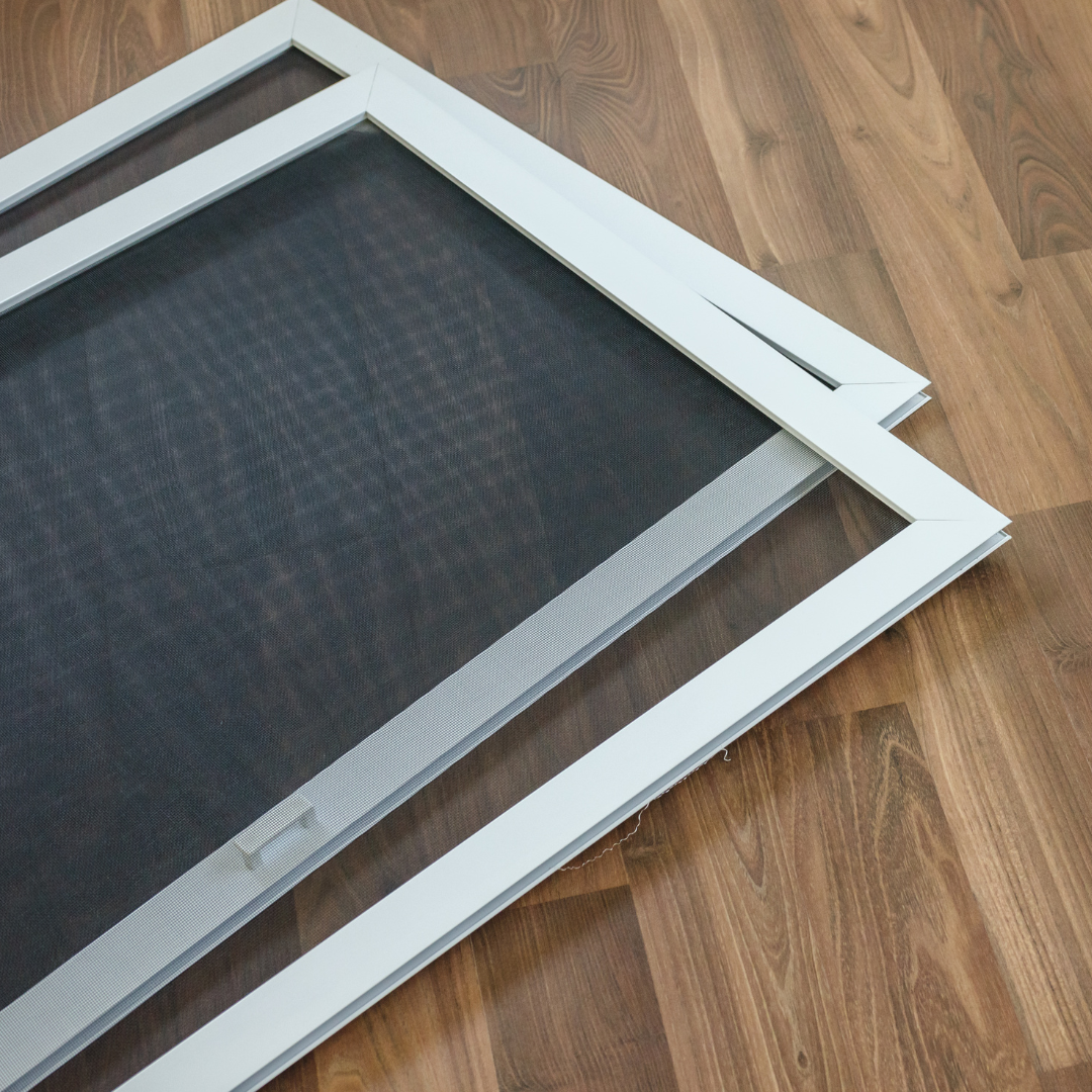 A pair of window screens laying on a wooden floor