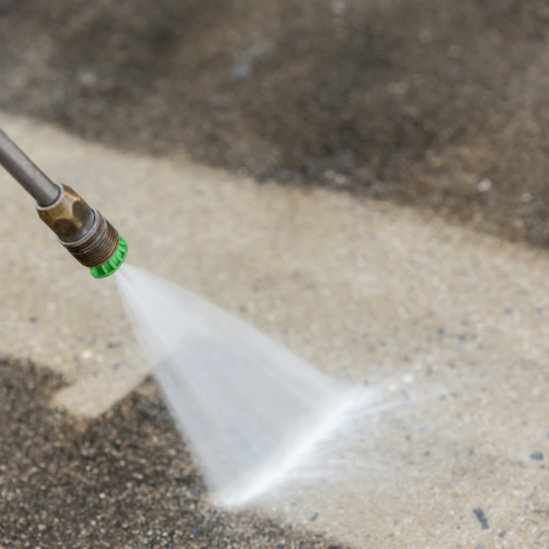 A person is using a high pressure washer to clean a concrete floor.