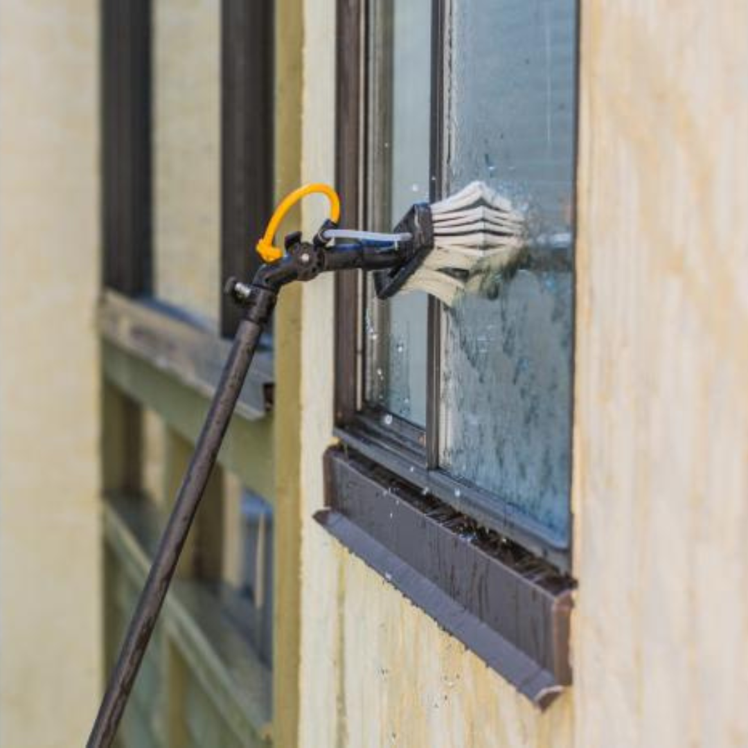 A brush is being used to clean a window on a building.