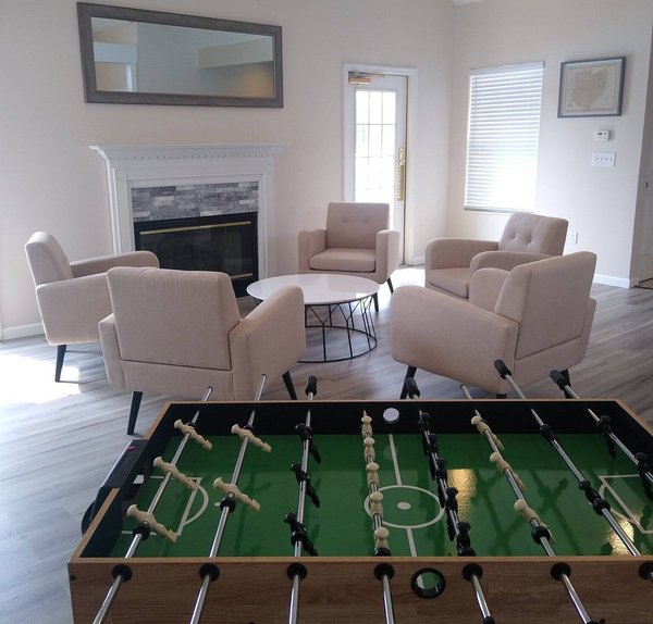 Living room with foosball table, fireplace, armchairs, and round coffee table.