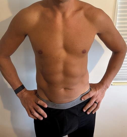 Man with hands on hips, wearing black boxer briefs, showing an athletic torso.