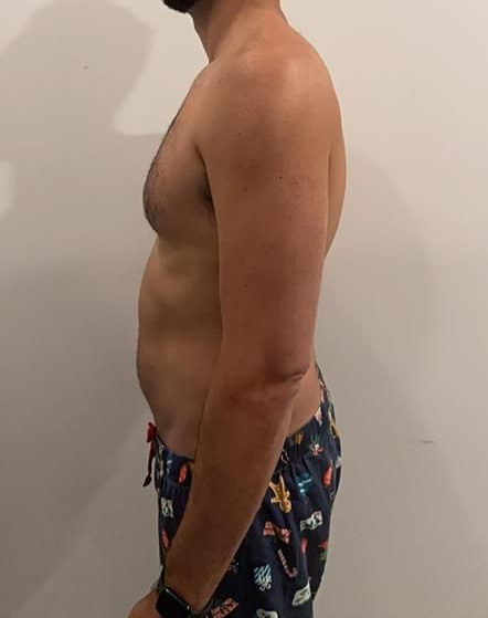 Woman in black athletic wear stands sideways near a wall.