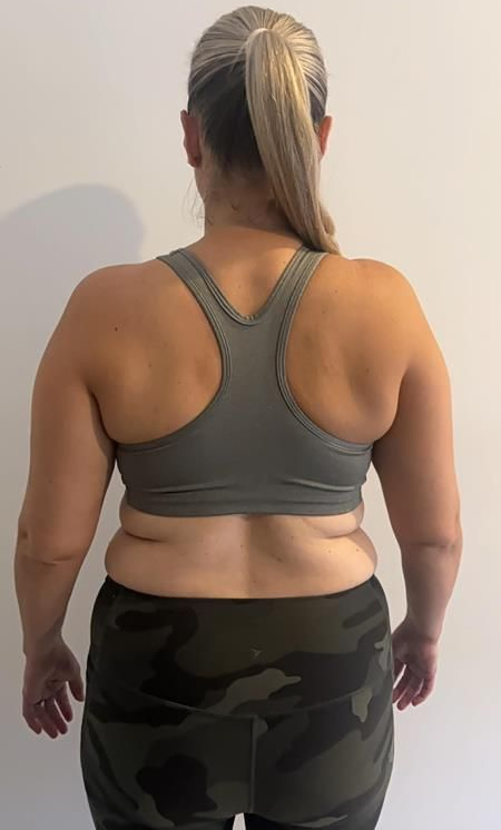 Person from the back wearing a gray sports bra and camo leggings; showing their back and shoulders.