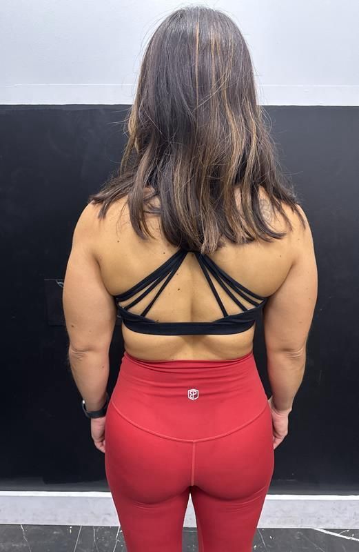 Woman in red leggings and black sports bra, back view.