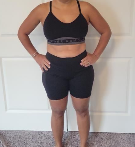 Woman in black sports bra and shorts with hands on hips.
