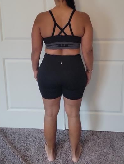 Person in black athletic wear stands with their back to the camera, against a white door.