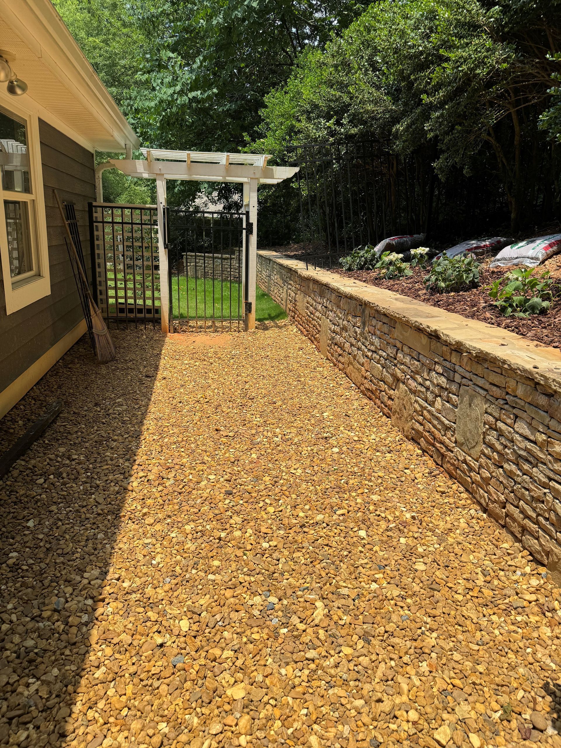A walkway leading to a house with gravel and a stone wall — Dawsonville, GA — Dixie Landscapes