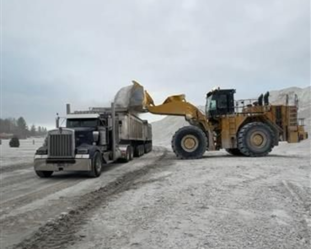 Construction dump truck unloading gravel with a hydraulic lift bed spilling material onto the ground, as a job site  
